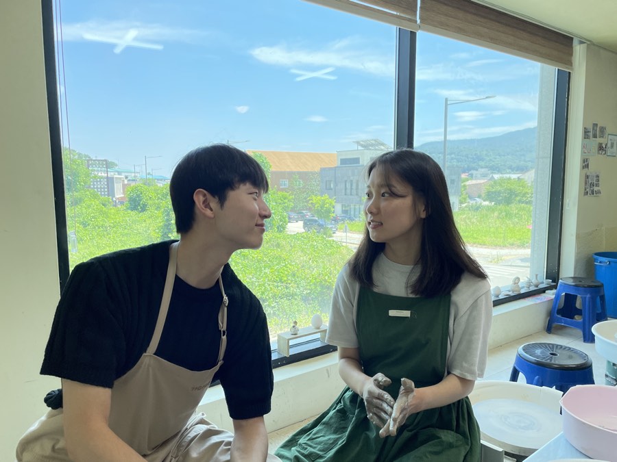 앞치마를 두르고 마주 앉아 요리하는 두 사람