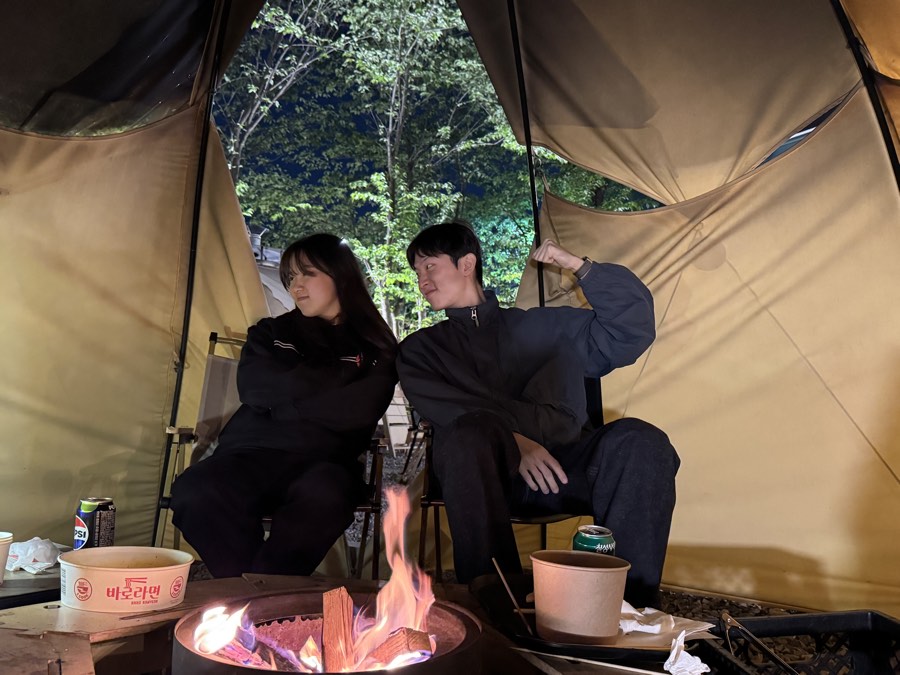 텐트 안에서 모닥불을 앞에 두고 앉은 두 사람